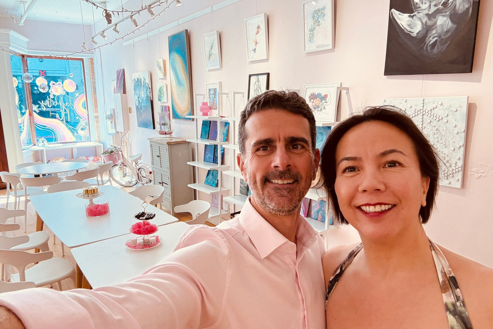 Nathan Motylinski and Cécile Hua of Stock Fragrance taking a selfie at the rose smelling session in Raleigh, NC, with the product table set up behind them in an art gallery