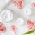 white cream and beauty products in round glass containers with pink flowers