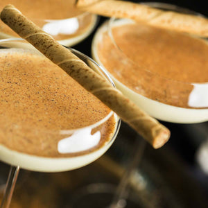 Two glasses of egg nog cocktail with a cinnamon stick on a blurred background; https://cdn.shopify.com/videos/c/o/v/6c853f172a9741559c892ae097293f2e.mp4