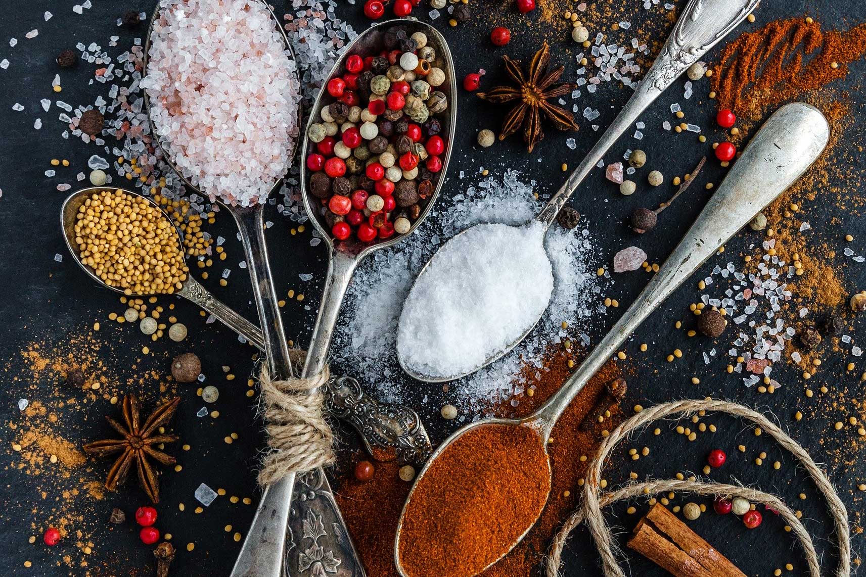 spices in antique spoons on dark background