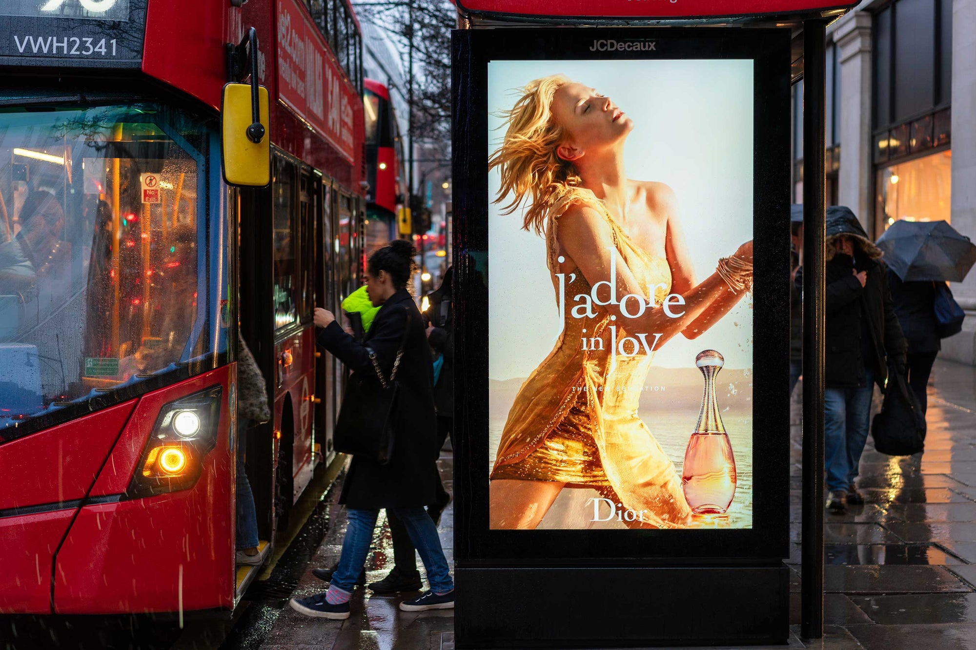 bus stop on rainy day with perfume advertisement showing woman in golden dress
