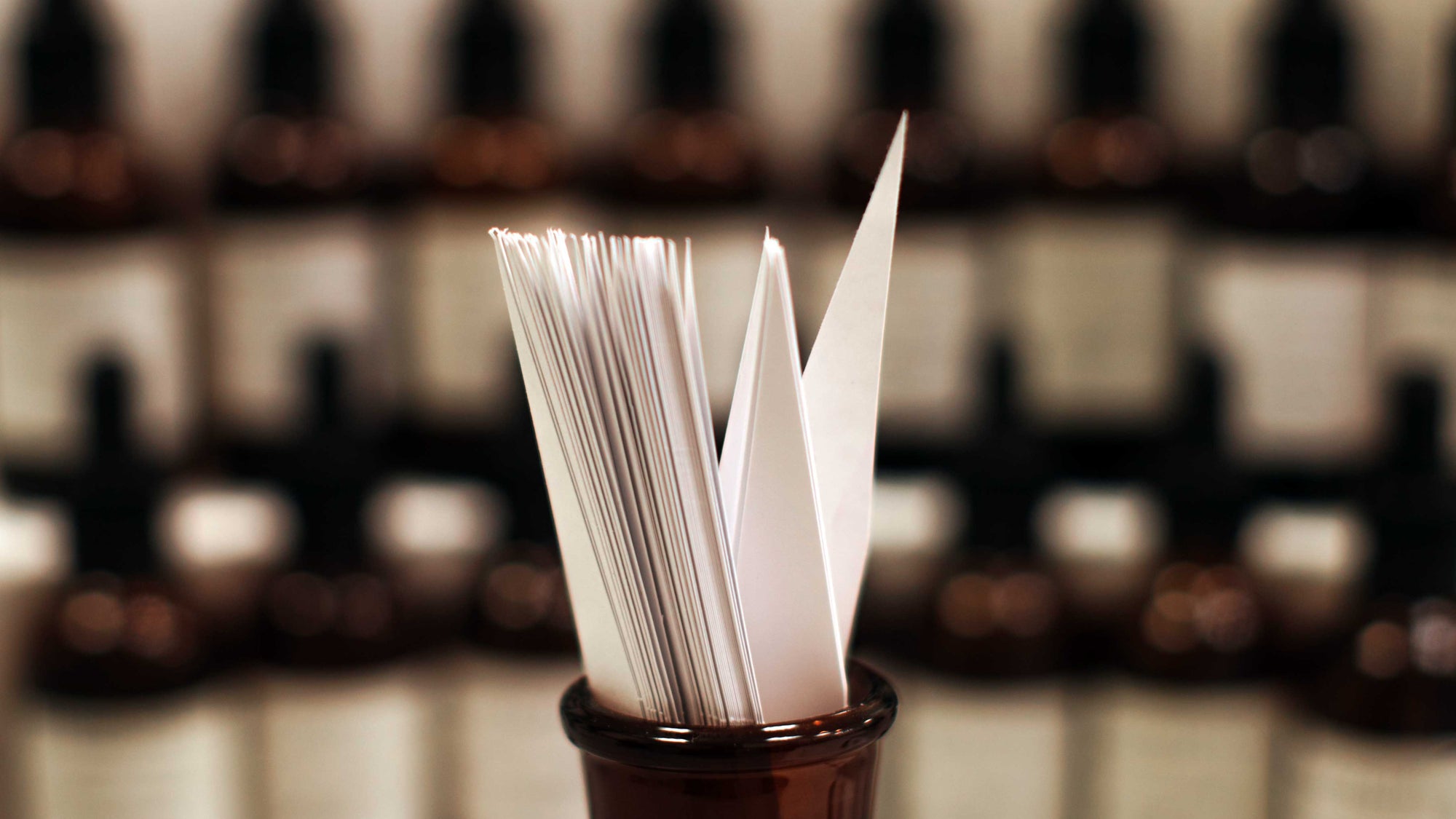Brown glass bottle with white papers inside, blurred wine bottles in the background