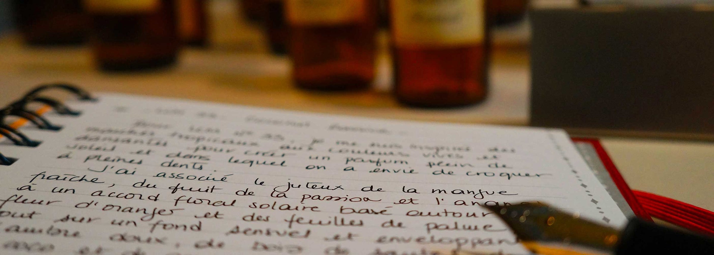 Open notebook with handwritten text on a wooden surface with bottles in the background