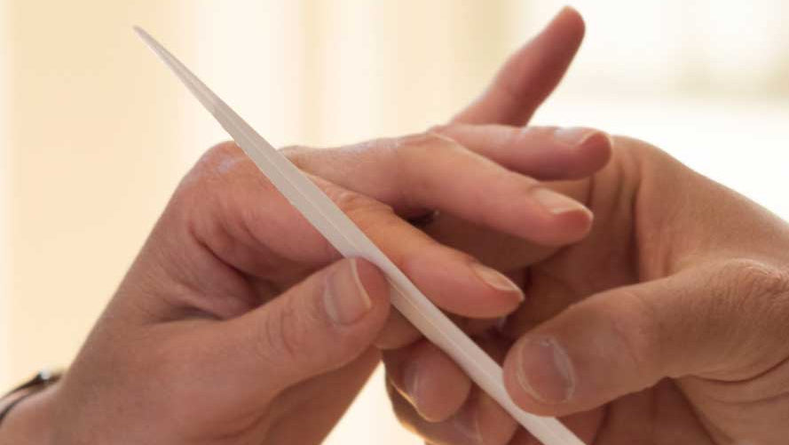 Close-up of hands holding a white object against a blurred background