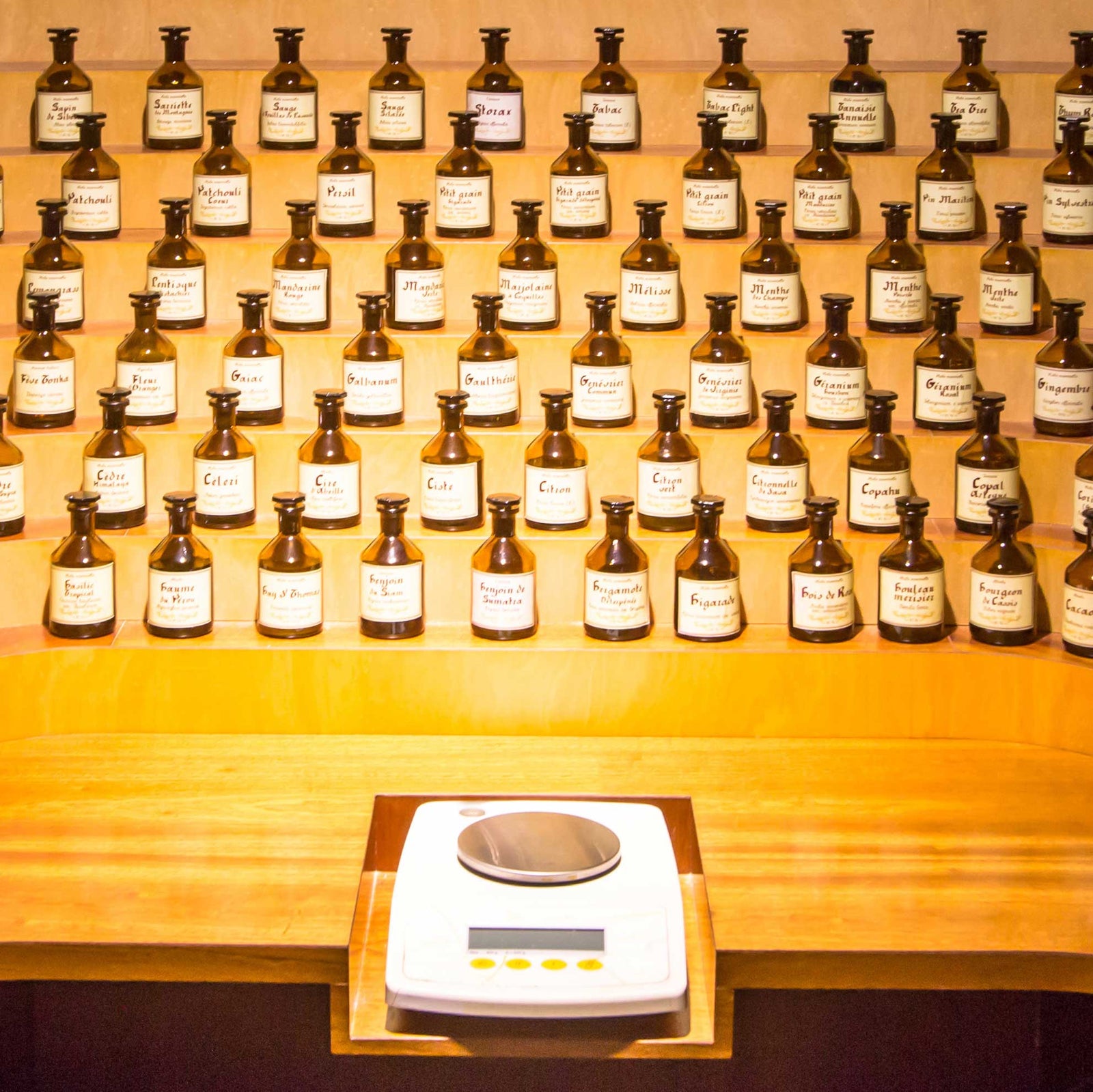 perfumers station with digital scale and perfume bottles on shelf