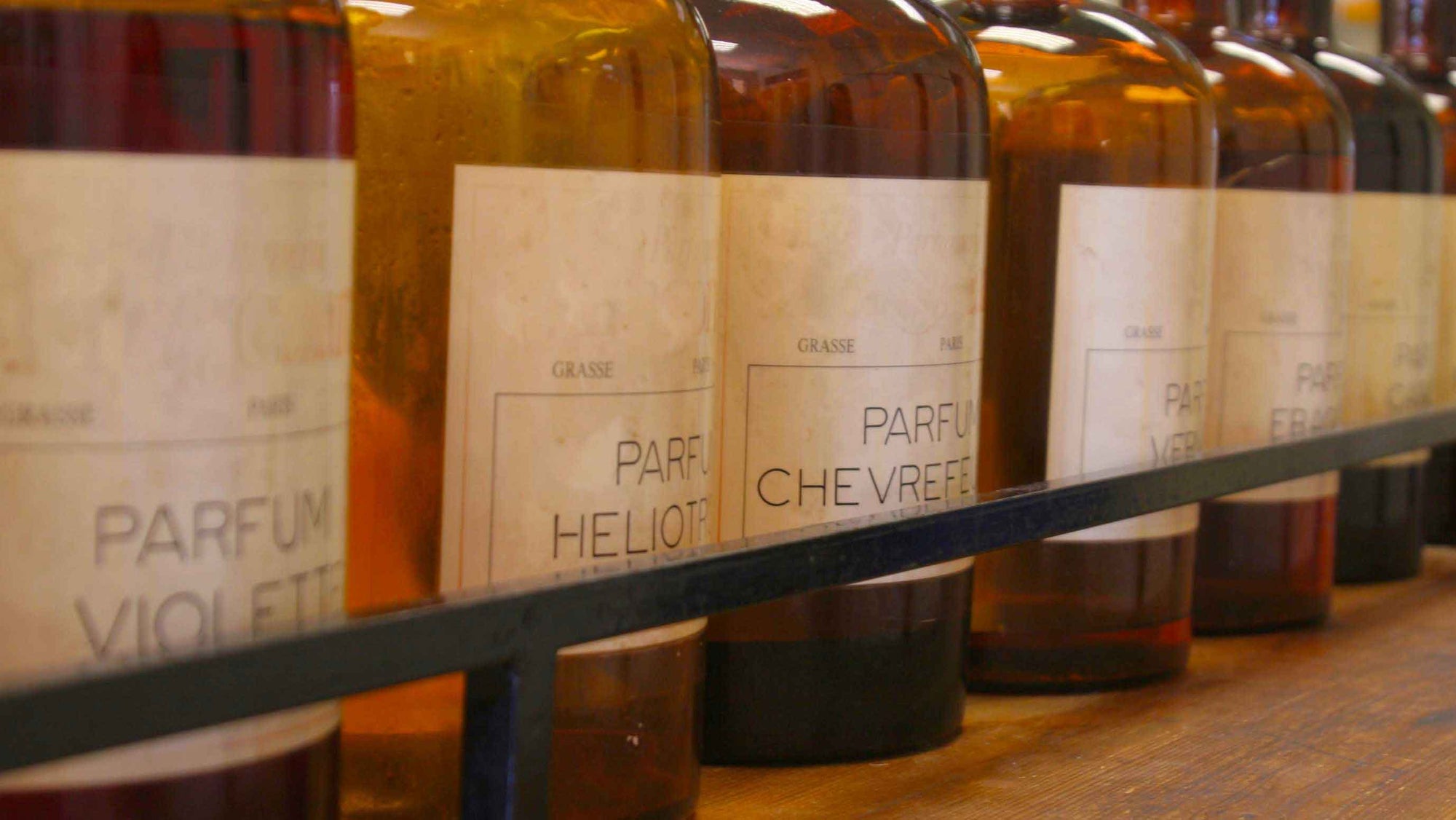 brown fragrance bottles on shelf with french names and labels